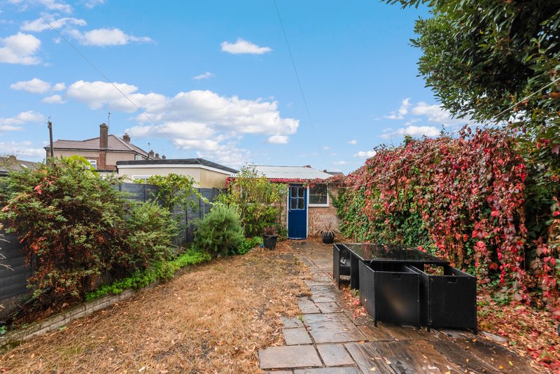 Brick cottage with blue door, gravel courtyard, ivy-covered walls and neighboring property visible