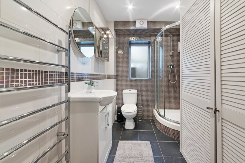Modern bathroom with pedestal sink, toilet, shower cubicle and heated towel rail