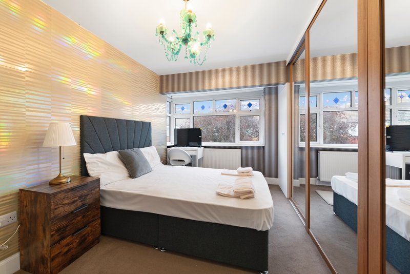 Modern bedroom with double bed, wooden nightstand, mirror wardrobe and contemporary lighting