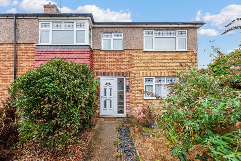 Brick semi-detached house with white windows, white door, and front garden with climbing ivy