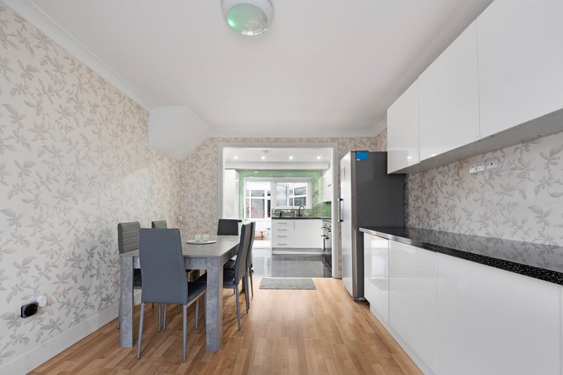 Modern kitchen-diner with dining table, white cabinetry, wood flooring and patterned wallpaper