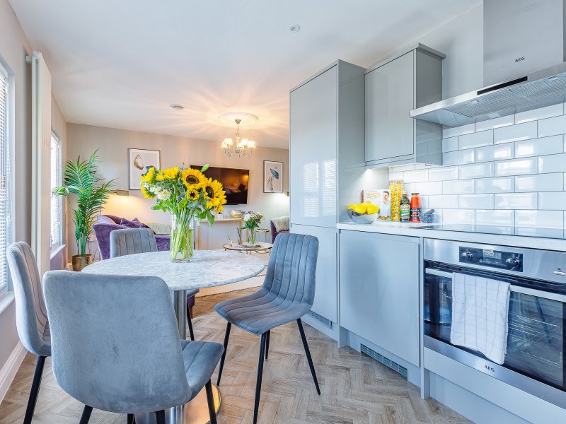 Open-plan kitchen and dining area with white cabinetry, dining table, and lounge seating visible