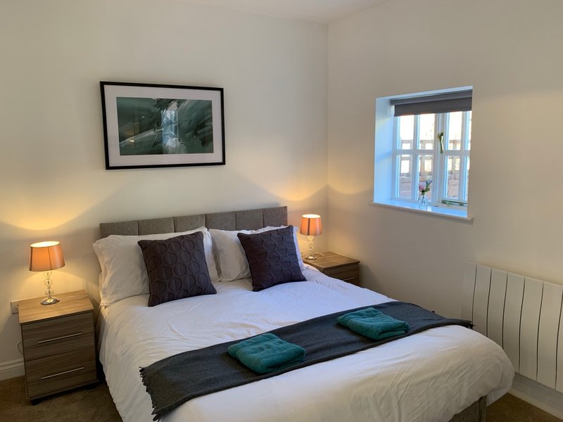 Bright modern bedroom with double bed, framed artwork, bedside lamps and window