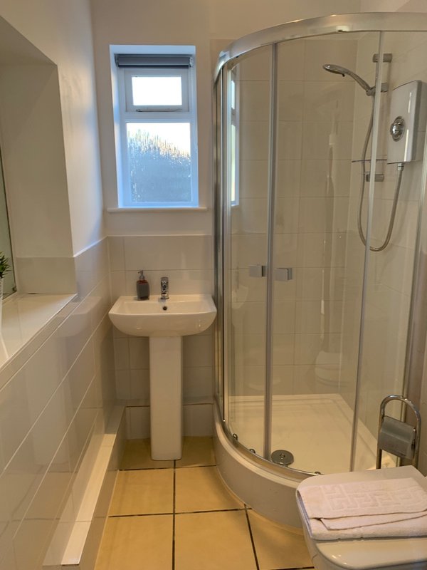 Modern bathroom with pedestal sink, shower cubicle, window and towel rail