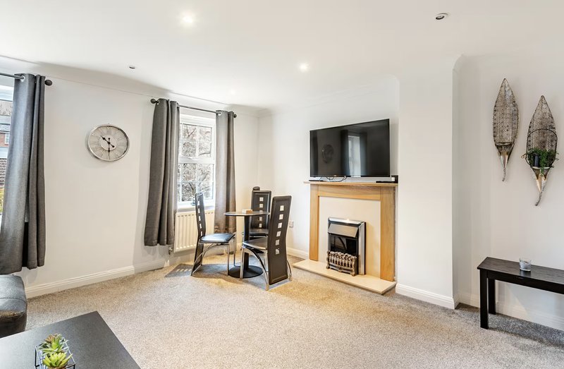 Spacious living room with fireplace, TV, dining table, and modern furnishings throughout