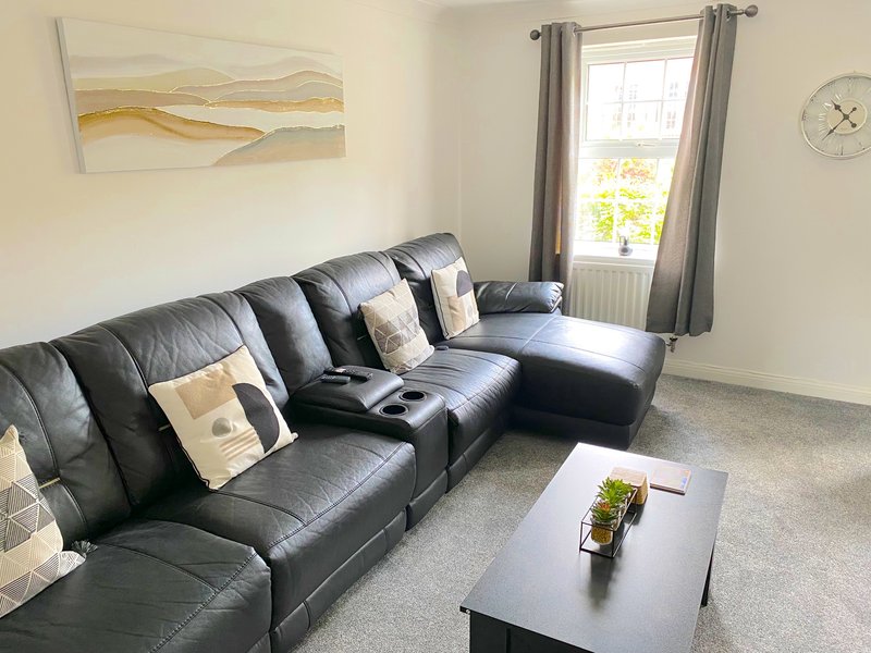 Living room with black leather sectional sofa, coffee table, and window with curtains