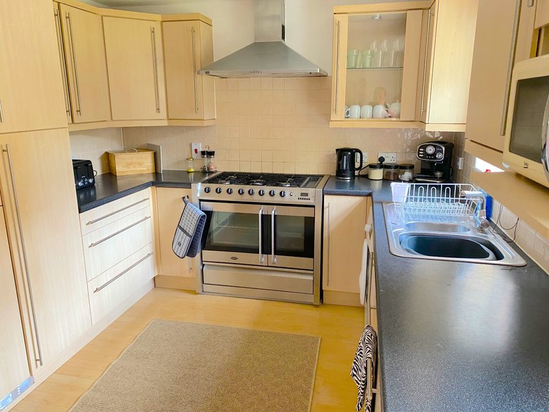 Modern kitchen with cream cabinets, stainless steel range cooker, dishwasher and granite worktops
