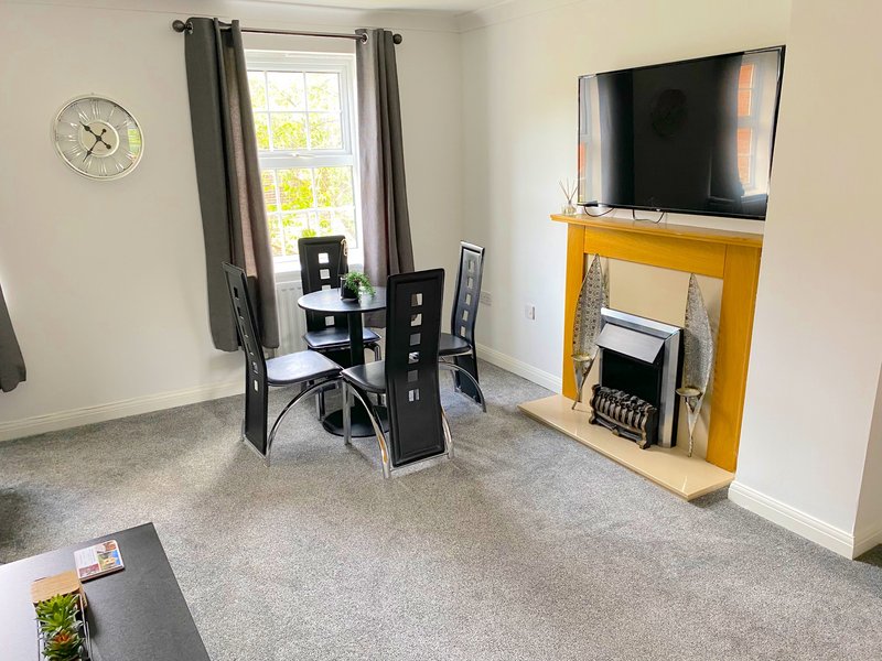 Living room with dining table, chairs, fireplace, wall-mounted TV and large window