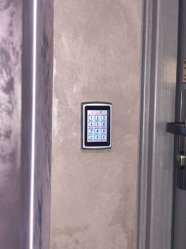 Digital keypad entry system mounted on beige wall beside door frame