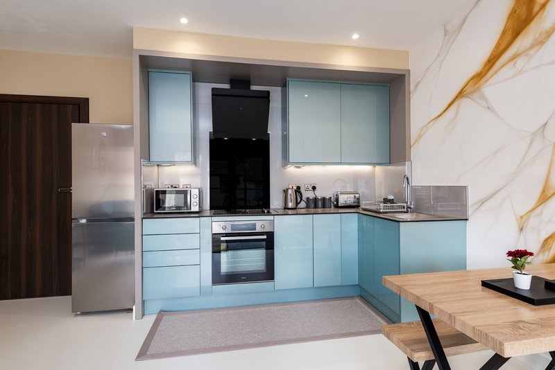 Modern kitchen with light blue cabinetry, stainless steel appliances, marble backsplash and wooden dining table