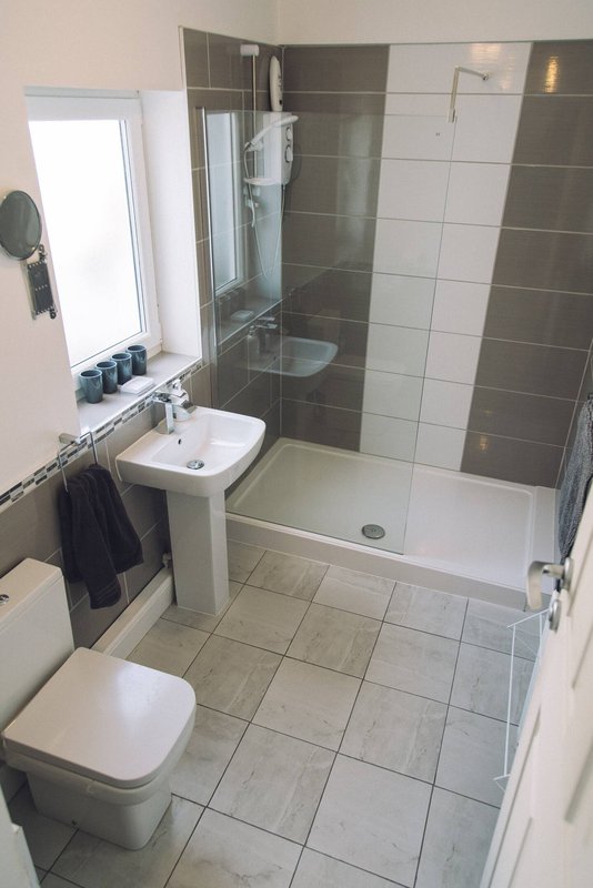 Modern bathroom with toilet, pedestal sink, mirror and walk-in shower with glass enclosure