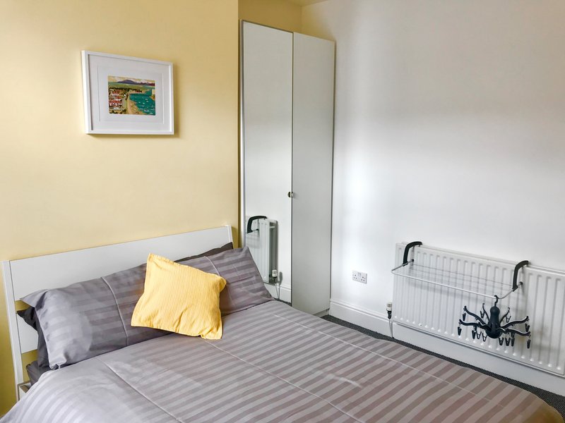 Bedroom with double bed, yellow and grey pillows, mirrored wardrobe, and yellow walls
