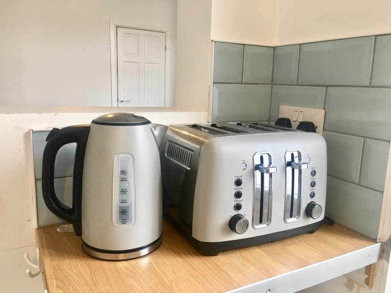 Kitchen counter with white kettle and toaster appliances next to tiled backsplash