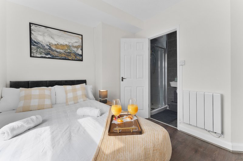 Modern bedroom with double bed, framed artwork, ensuite bathroom and radiator