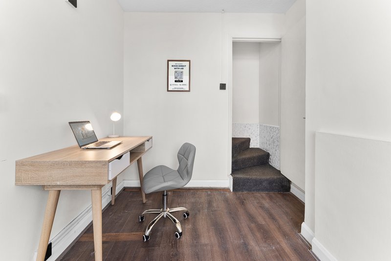 Modern home office with wooden desk, office chair, laptop and framed wall art
