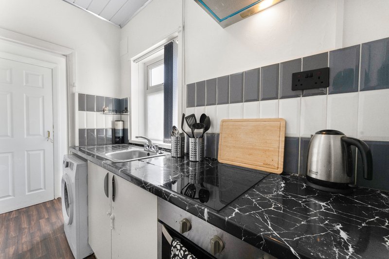 Modern kitchen with white cabinetry, black marble countertop, stainless steel appliances and tiled backsplash