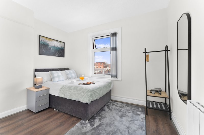 Bright bedroom with double bed, wooden floor, window with city view, and modern furnishings