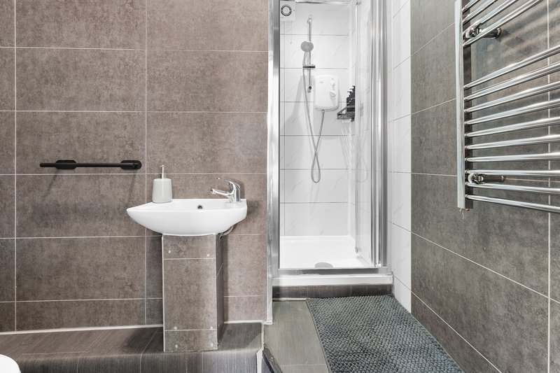 Modern bathroom with pedestal sink, walk-in shower, and heated towel rail