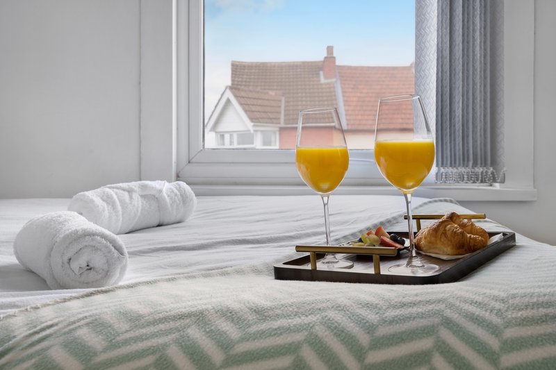 Bedroom window view with rolled towels, orange juice glasses and croissants on tray