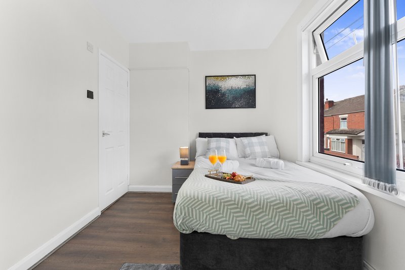 Bright bedroom with double bed, wooden floor, large windows and wall art