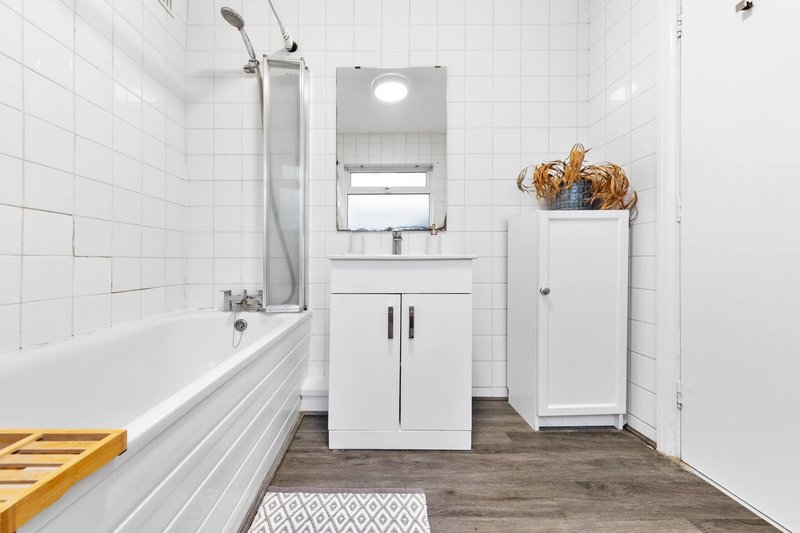 Clean white bathroom with bathtub, vanity sink, mirror and woven basket storage