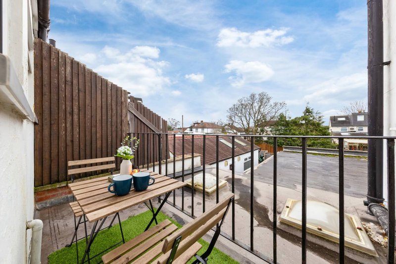 Rooftop terrace with wooden decking, black metal railings, potted plants and folding chairs