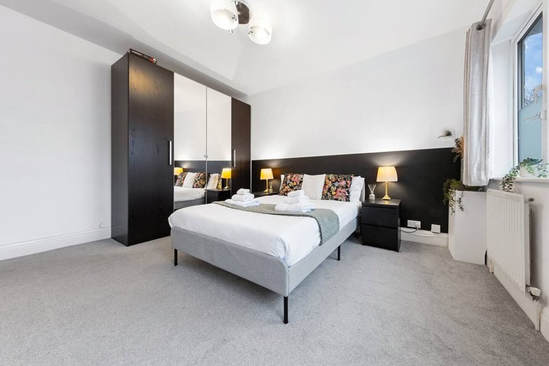 Modern bedroom with double bed, black headboard, mirrored wardrobe and bedside lamps