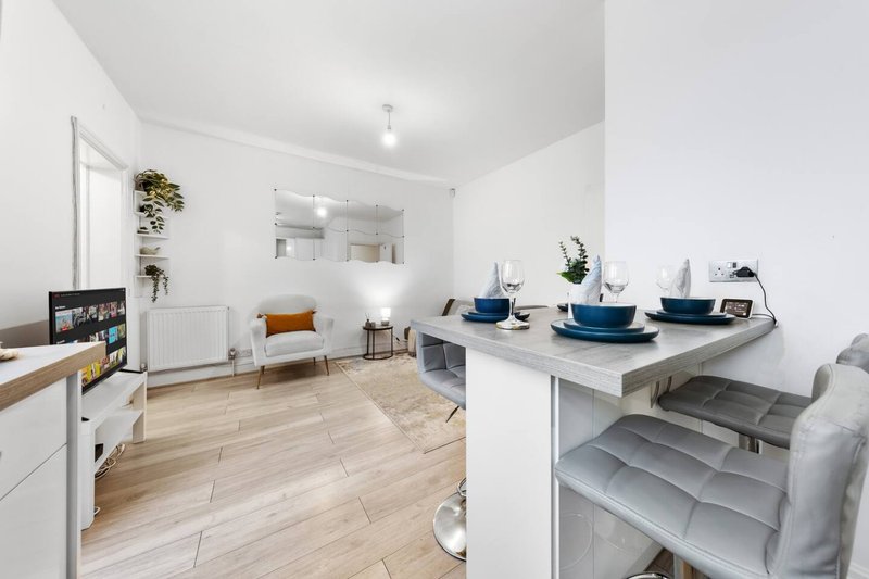 Open-plan studio with kitchen island, wooden flooring, white walls and modern furnishings