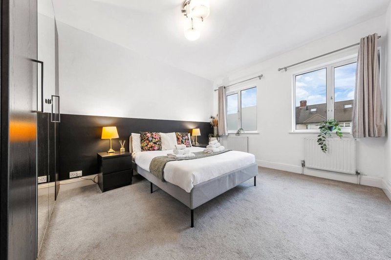 Modern bedroom with double bed, black accent wall, bedside lamps and large windows