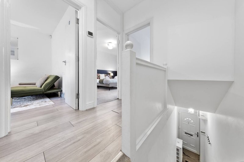 Modern hallway with wood-effect flooring, white walls, open doors to bedroom and living areas