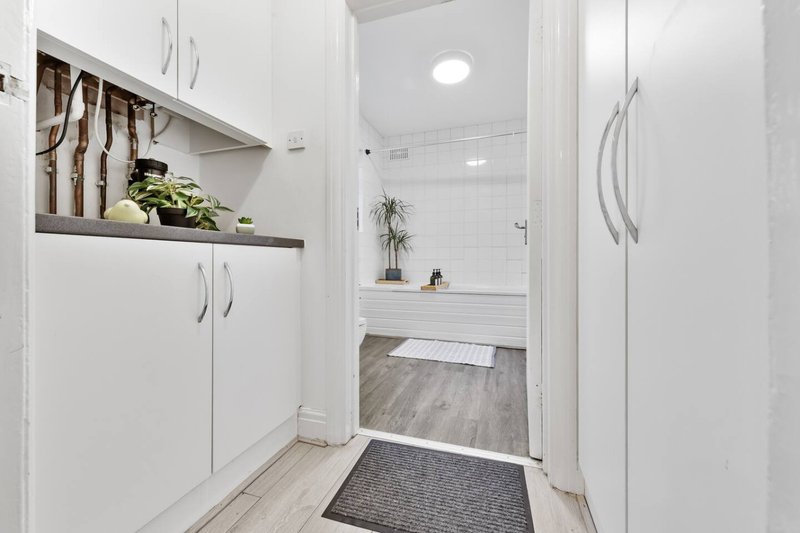 Modern bathroom with white vanity, open shelving, potted plants and walk-in shower