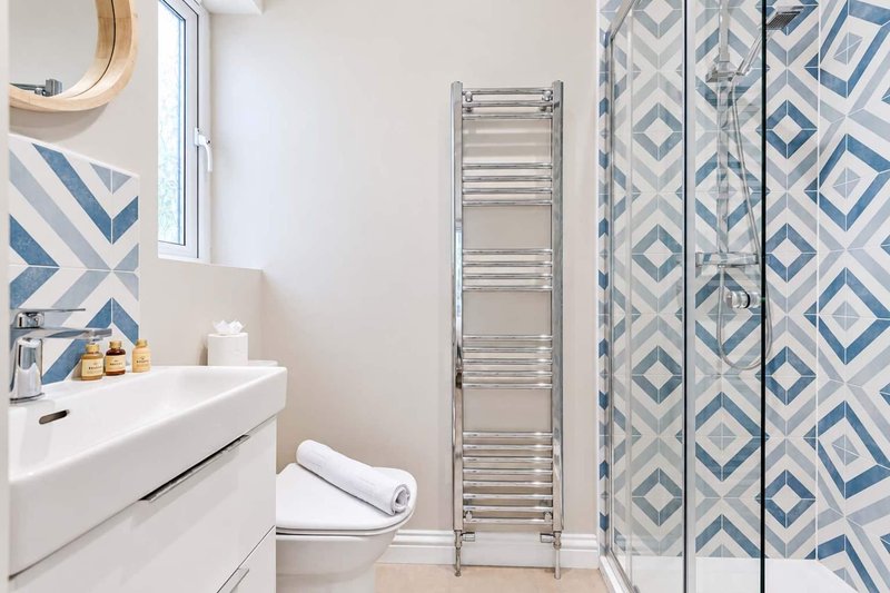 Modern bathroom with white vanity, towel rail, patterned shower curtain and window