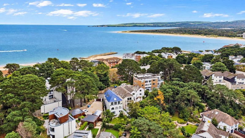 Aerial view of coastal residential neighborhood with beach, bay, and tree-lined streets