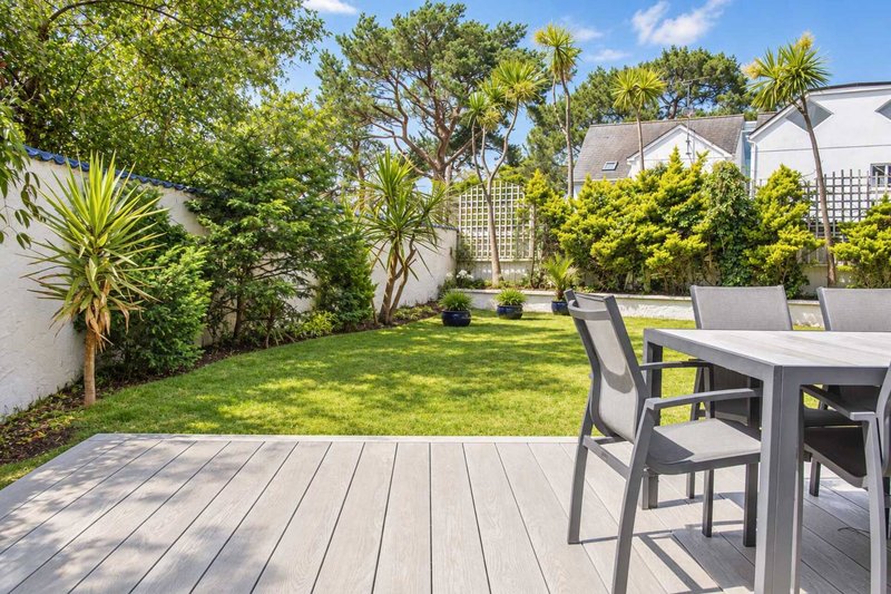 Modern garden with composite decking, outdoor dining table, and lush landscaping