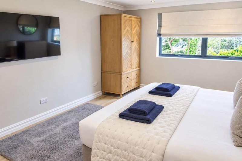 Modern bedroom with double bed, wooden wardrobe, wall-mounted TV and garden views