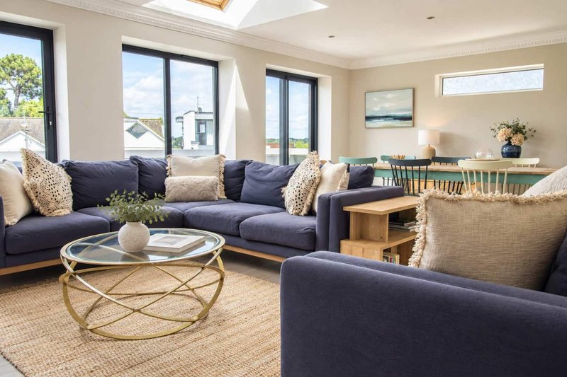 Spacious living room with navy blue sofa, armchair, round coffee table and large windows overlooking garden