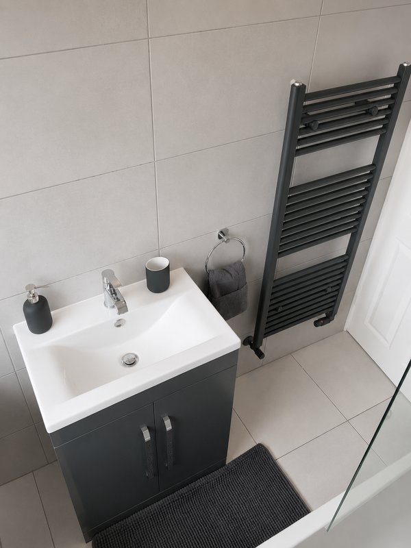 Modern bathroom with white sink, black vanity cabinet, heated towel rail and tiled walls
