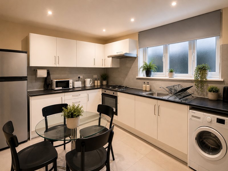 Modern kitchen with white cabinets, black countertops, dining table and stainless steel appliances