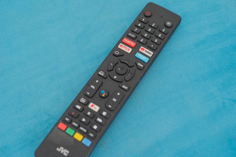 Black remote control with colored buttons on blue fabric surface