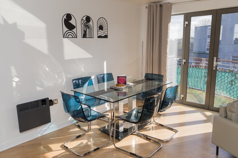 Bright modern dining area with glass table, blue chairs, and city views through large windows
