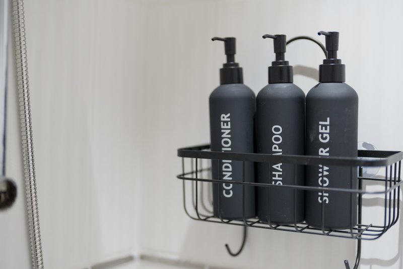 Bathroom shelf with three black pump bottles of toiletries and shower caddy
