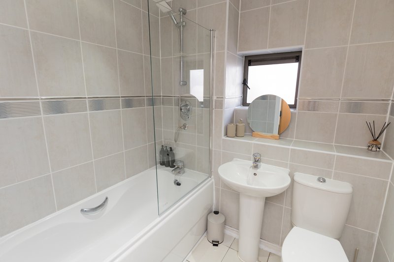 Modern bathroom with white tile walls, shower cubicle, basin, toilet and mirror