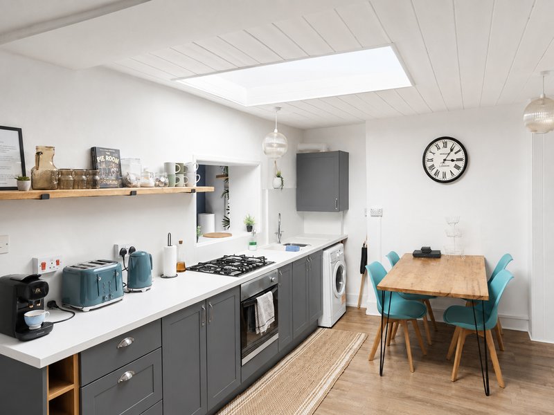 itchen with dark cabinetry, white countertop, dining table with teal chairs