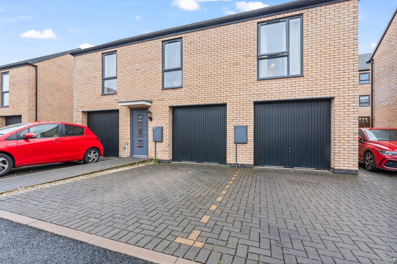 Modern brick townhouse with double garage, driveway, and parked red car