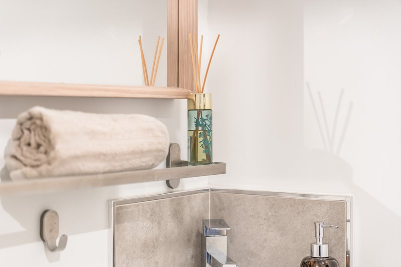 Minimalist bathroom shelf with rolled towel, reed diffuser, and soap dispenser