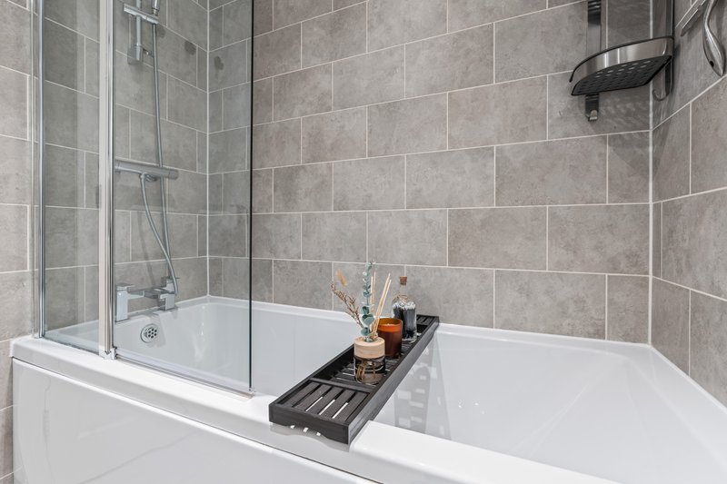 Modern bathroom with dual bathtub, glass shower enclosure, tiled walls and bathroom accessories