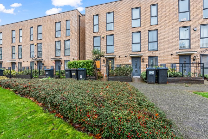 Brick apartment building exterior with manicured garden, hedges and paved courtyard