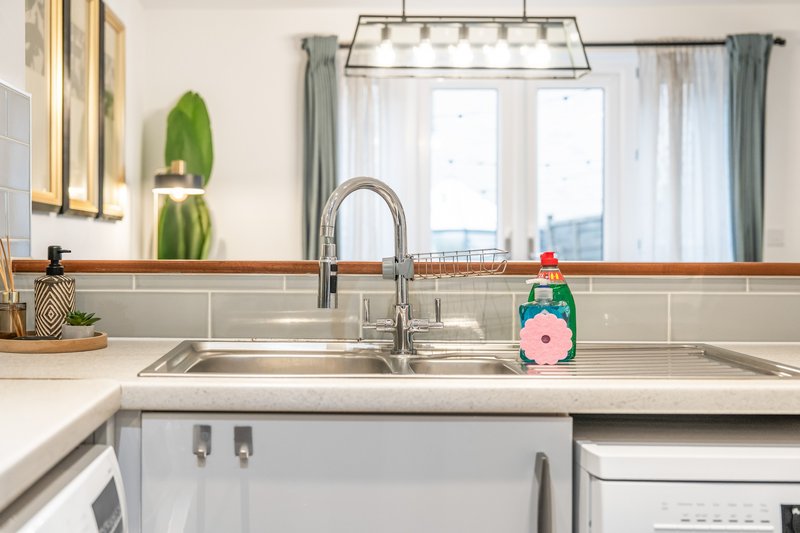 Modern kitchen with double sink, chrome faucet, white cabinetry and pendant lighting