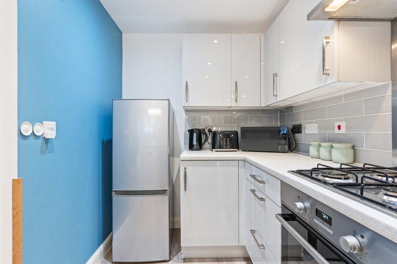 Modern kitchen with white cabinetry, stainless steel appliances, blue accent wall and gas cooktop