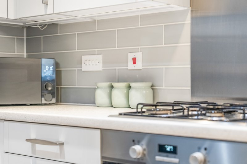 Modern kitchen with gas hob, white subway tile splashback, and green storage containers